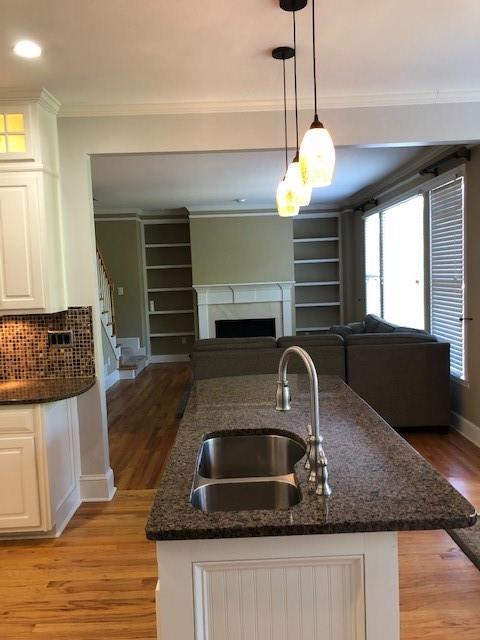 kitchen featuring decorative light fixtures, sink, white cabinets, and dark stone counters
