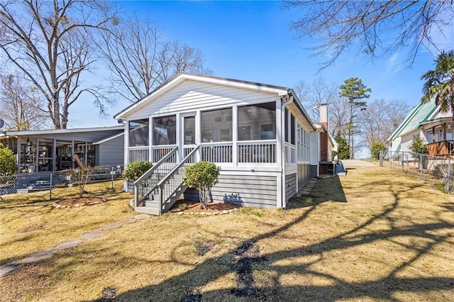 exterior space featuring stairway, fence, a sunroom, a chimney, and a front lawn