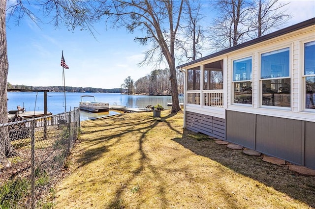 view of yard with a water view, a sunroom, a boat dock, and fence