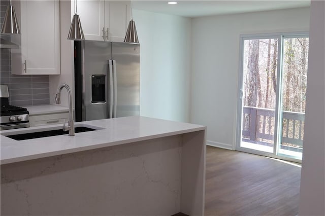 kitchen featuring white cabinetry, stainless steel appliances, backsplash, light stone countertops, and sink