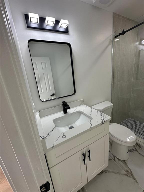 bathroom with vanity, toilet, and tiled shower