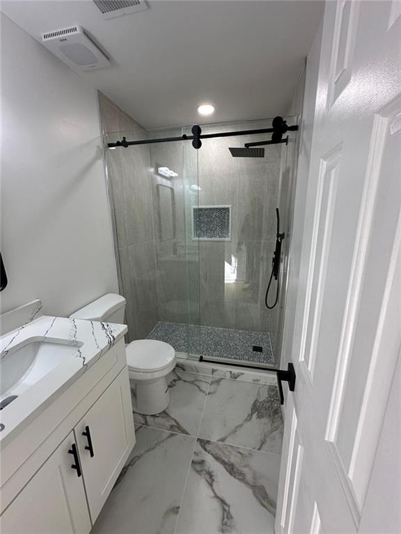 bathroom featuring vanity, an enclosed shower, and toilet