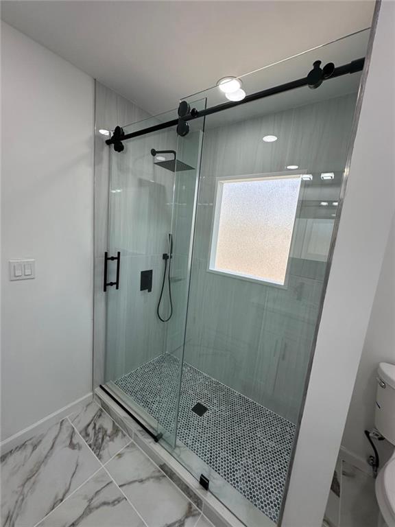 bathroom featuring a shower with shower door and toilet