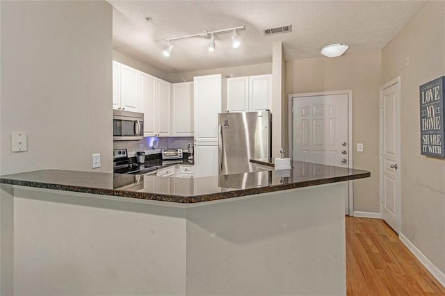 10 Perimeter Summit Blvd NE Unit 4223, Brookhaven, GA 30319 - kitchen featuring appliances with stainless steel finishes, a peninsula, light wood finished floors, white cabinets, and a textured ceiling