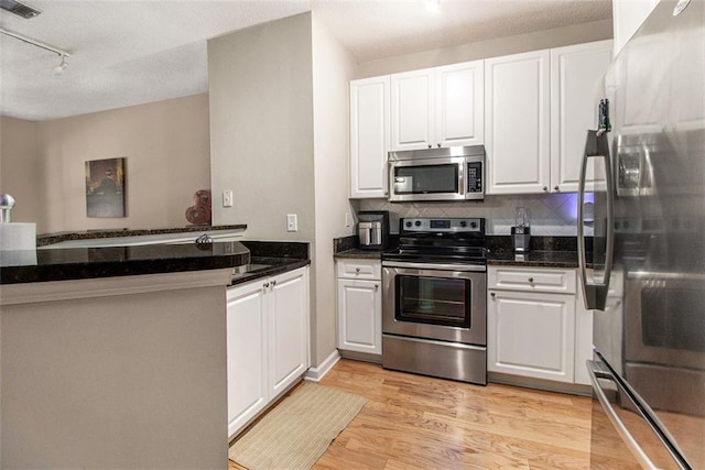 10 Perimeter Summit Blvd NE Unit 4223, Brookhaven, GA 30319 - kitchen featuring stainless steel appliances, light wood finished floors, white cabinetry, decorative backsplash, and a textured ceiling