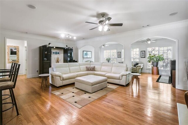 living room with light wood-type flooring, ceiling fan, and crown molding