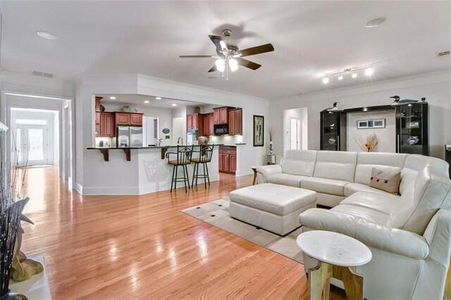 living room featuring light hardwood / wood-style floors, ceiling fan, and crown molding