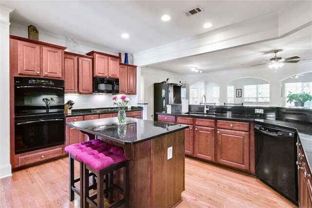 kitchen with light hardwood / wood-style flooring, sink, black appliances, and a center island