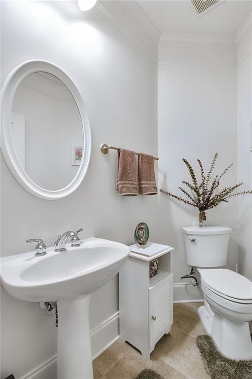 bathroom with tile patterned floors, toilet, and crown molding