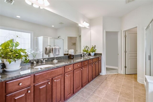 bathroom with tile patterned flooring, vanity, and a shower with door