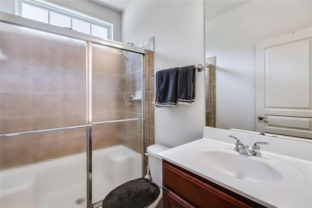 bathroom with toilet, vanity, and a shower with door