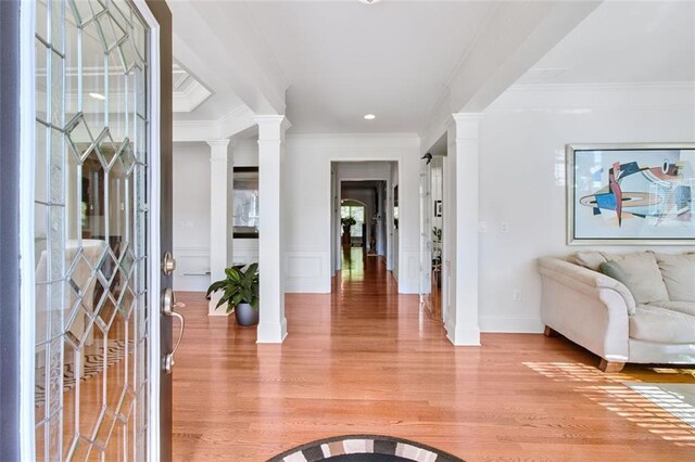 foyer entrance featuring crown molding, ornate columns, and light hardwood / wood-style flooring