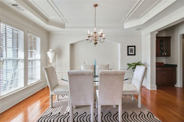 dining area with a chandelier, a tray ceiling, light wood-type flooring, and ornamental molding