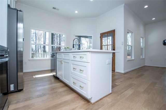 90 Ayers Rd, Bowdon, GA 30108 - kitchen featuring crown molding, light wood-type flooring, white cabinetry, a kitchen island with sink, and recessed lighting