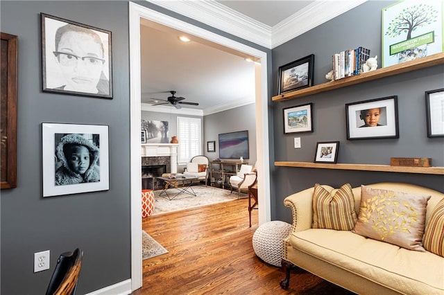 sitting room featuring a ceiling fan, wood finished floors, a high end fireplace, and crown molding