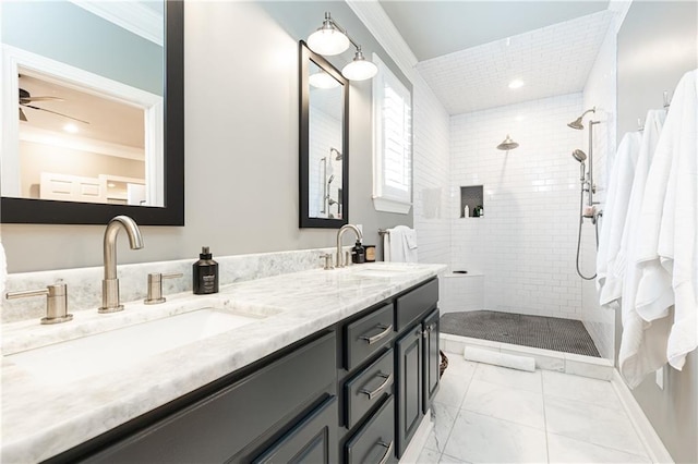 bathroom featuring ceiling fan, a sink, a tile shower, and double vanity