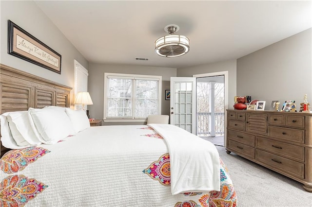 bedroom with access to exterior, visible vents, and light colored carpet