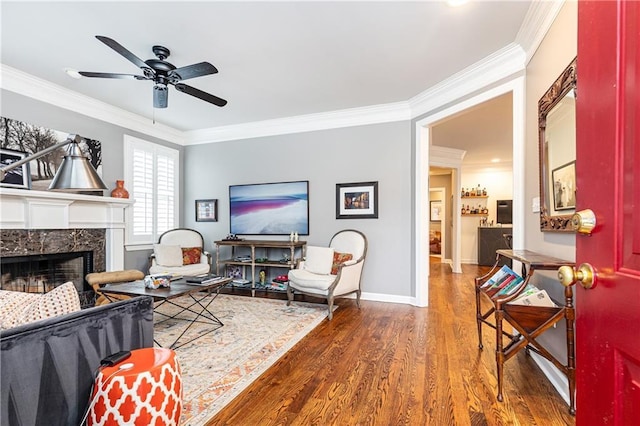 living area with crown molding, baseboards, wood finished floors, and a high end fireplace