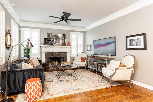 living area featuring ceiling fan, wood finished floors, a high end fireplace, baseboards, and crown molding