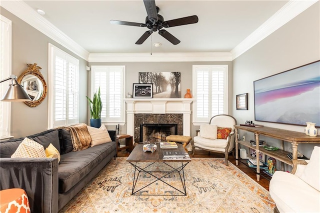 living area featuring a fireplace, a ceiling fan, and crown molding