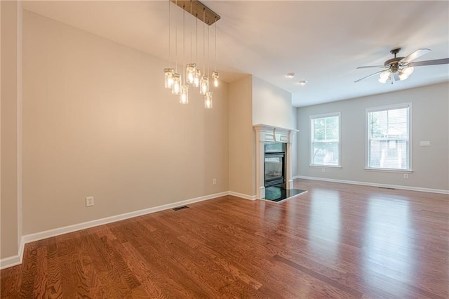 4404 Village Field Pl, Suwanee, GA 30024 - unfurnished living room with wood finished floors, ceiling fan, baseboards, a high end fireplace, and a chandelier