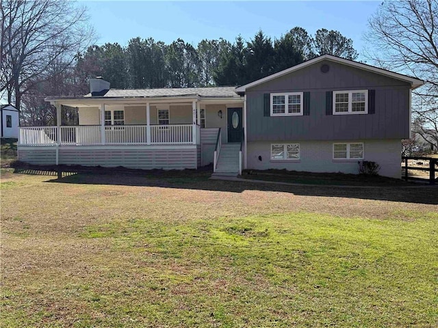 split level home featuring a porch, a chimney, and a front yard