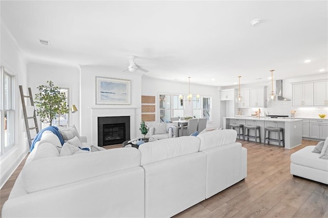 3317 Stillwood Ln, Hapeville, GA 30354 - living room with recessed lighting, visible vents, a glass covered fireplace, light wood-type flooring, and ceiling fan with notable chandelier