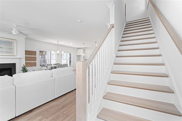 3317 Stillwood Ln, Hapeville, GA 30354 - staircase with a fireplace, wood finished floors, and ceiling fan with notable chandelier