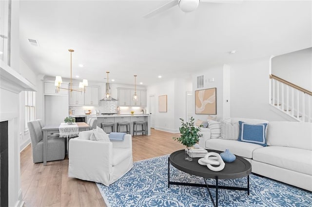 living room featuring light wood-type flooring, visible vents, and stairway