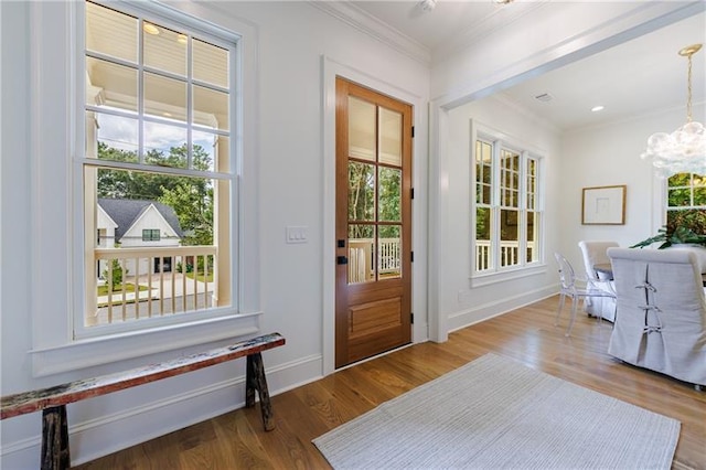 doorway featuring crown molding, wood-type flooring, and an inviting chandelier