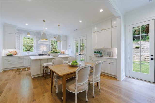 dining area featuring light wood-type flooring and crown molding