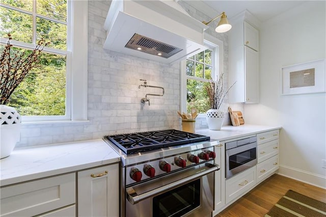 kitchen with backsplash, built in microwave, white cabinetry, and stainless steel stove