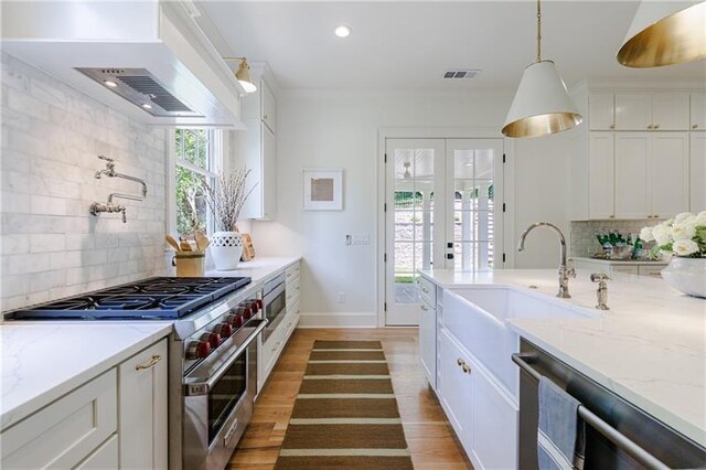 kitchen with tasteful backsplash, white cabinetry, hanging light fixtures, and stainless steel appliances