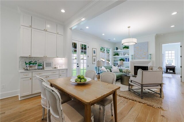 dining room featuring french doors, light hardwood / wood-style floors, and crown molding