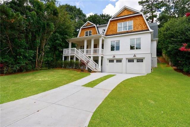 shingle-style home featuring a front yard, covered porch, a gambrel roof, and concrete driveway