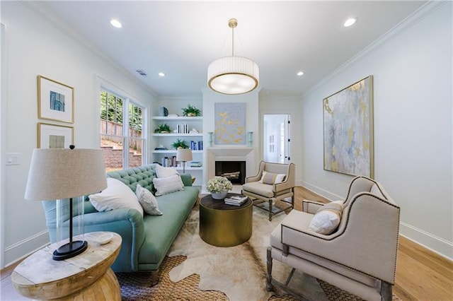 living room with light hardwood / wood-style flooring, built in features, and crown molding