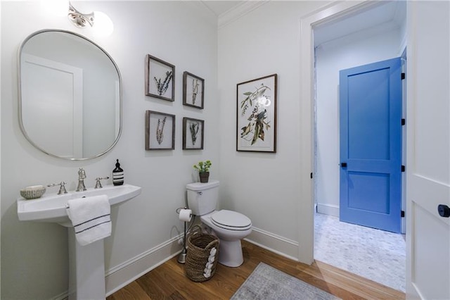 bathroom with wood-type flooring, toilet, and crown molding