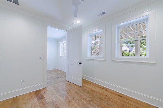 empty room with light hardwood / wood-style floors and crown molding