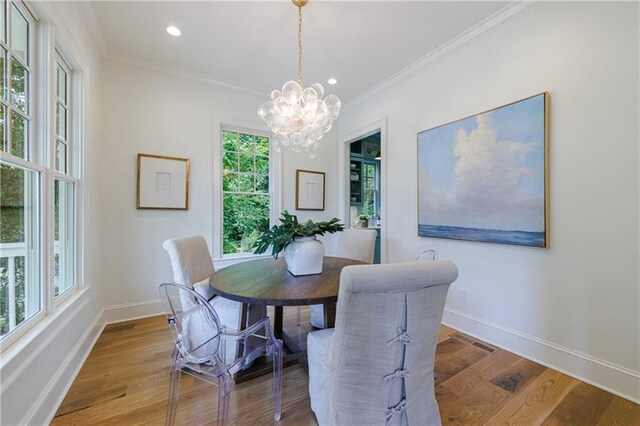 dining room with crown molding, wood-type flooring, and a notable chandelier