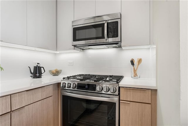 kitchen featuring stainless steel appliances, light countertops, decorative backsplash, and modern cabinets