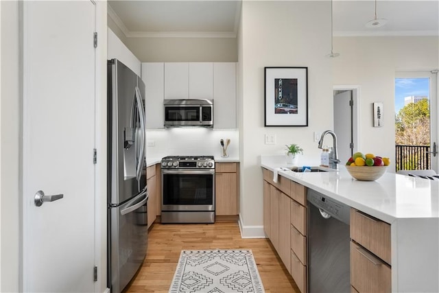 kitchen with stainless steel appliances, crown molding, a sink, and a peninsula