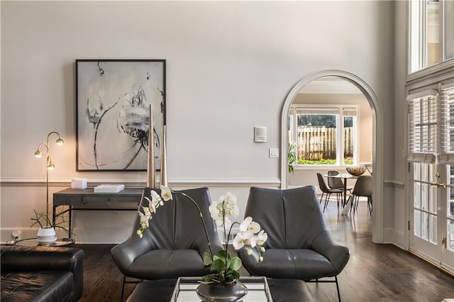 living area featuring arched walkways and wood finished floors