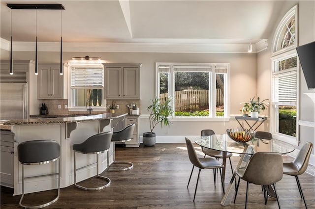 kitchen with gray cabinets, stone countertops, a kitchen bar, dark wood-style floors, and built in fridge