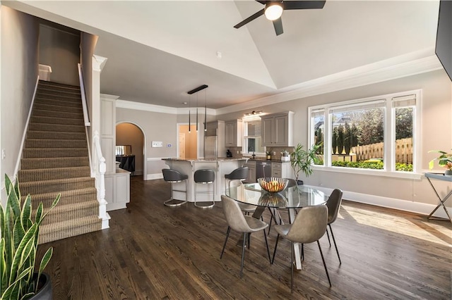 dining space with stairs, a ceiling fan, arched walkways, ornamental molding, and dark wood-type flooring
