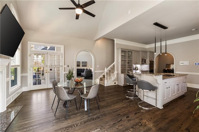 dining room featuring arched walkways, dark wood-style floors, crown molding, and ceiling fan