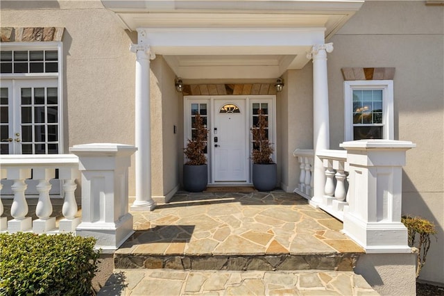 doorway to property with french doors, stucco siding, and covered porch