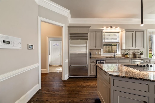 kitchen featuring gray cabinets, a sink, stainless steel built in fridge, decorative backsplash, and ornamental molding