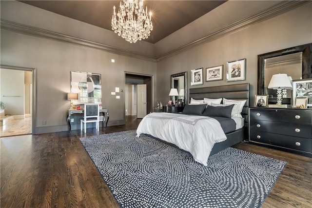 bedroom featuring an inviting chandelier, ornamental molding, baseboards, and wood finished floors