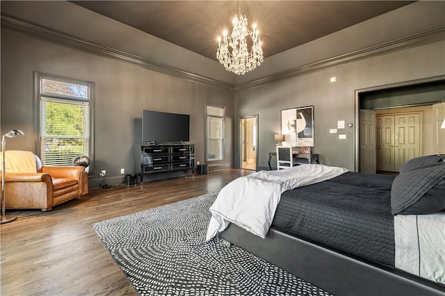 bedroom with baseboards, ornamental molding, wood finished floors, a raised ceiling, and a notable chandelier