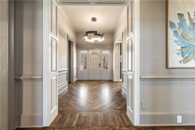 foyer entrance featuring a decorative wall, crown molding, and a notable chandelier